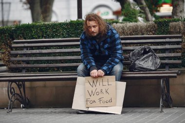 Güz şehrinde durgun elbiseli evsiz bir adam.