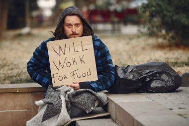 Güz şehrinde durgun elbiseli evsiz bir adam.