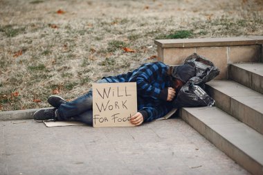 Güz şehrinde durgun elbiseli evsiz bir adam.