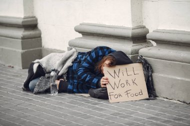 Güz şehrinde durgun elbiseli evsiz bir adam.