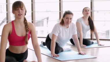 Hamile kadın bir eğitmenle bacak esnetiyor.