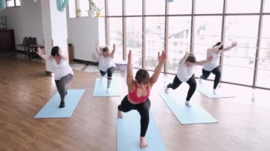 Modern bir spor salonunda bir eğitmenle esneme egzersizleri yapan kadınlar.