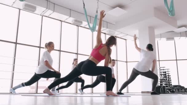 Mujeres haciendo ejercicios de estiramiento en un gimnasio moderno con un instructor — Vídeos de Stock