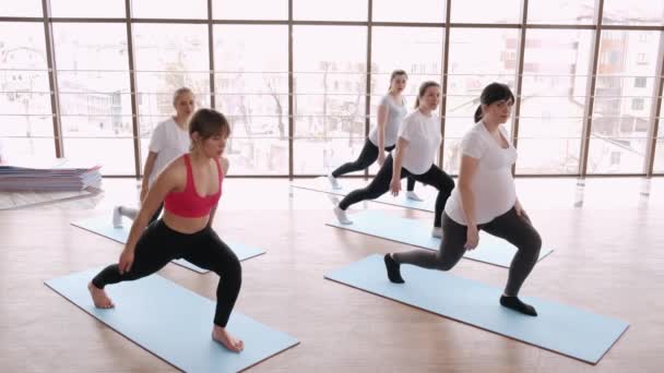 Modern bir spor salonunda bir eğitmenle esneme egzersizleri yapan kadınlar. — Stok video