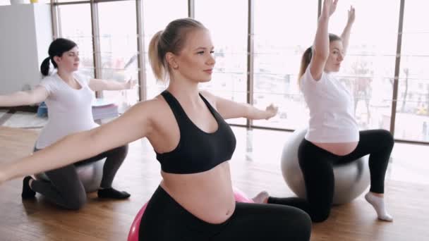 Беременные женщины делают предродовые упражнения на фитнес-мячах в тренажерном зале — стоковое видео