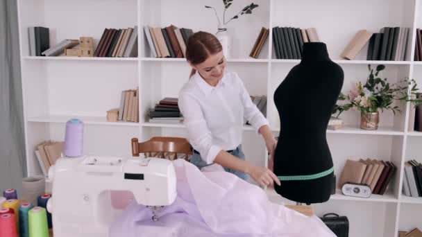 Красива жінка кравець вимірює форму сукні стрічкою — стокове відео
