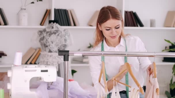 Un sarto professionista femminile apprezza un vestito su un appendiabiti — Video Stock