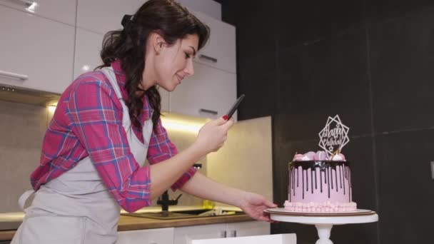 Kvinnlig bagare tar ett foto av en födelsedagstårta i ett kök — Stockvideo