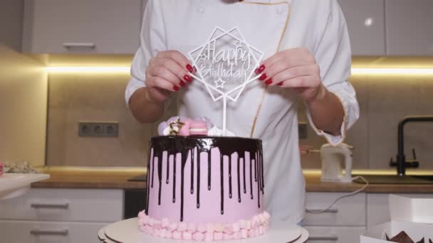 Woman baker is setting happy birthday decoration on a cake — Stock Video