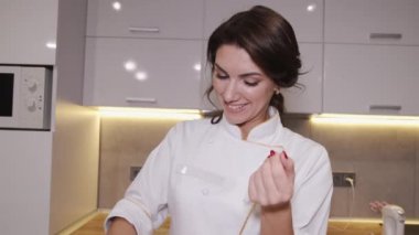 Güzel kadın pastacı mutfakta lezzetli makaronlar pişiriyor.