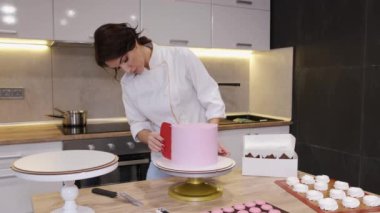 Kadın fırıncı modern bir mutfakta doğum günü pastası yapıyor.