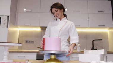 Kadın fırıncı modern bir mutfakta doğum günü pastası yapıyor.