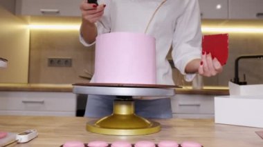 Kadın fırıncı mutfakta lezzetli pembe bir pasta yapıyor.