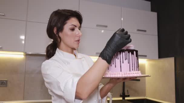 Mujer panadero está decorando un pastel de cumpleaños con macarrones en la parte superior — Vídeos de Stock