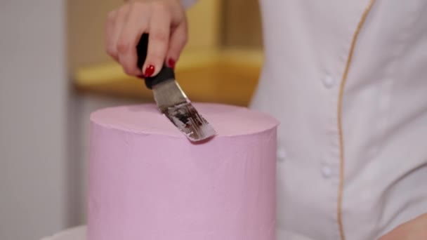 女パン屋さんがキッチンでおいしいピンクケーキを作っています — ストック動画