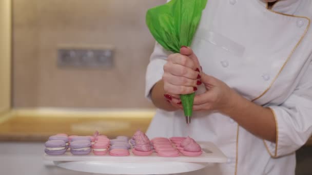 Een lachende bakker maakt macarons. — Stockvideo