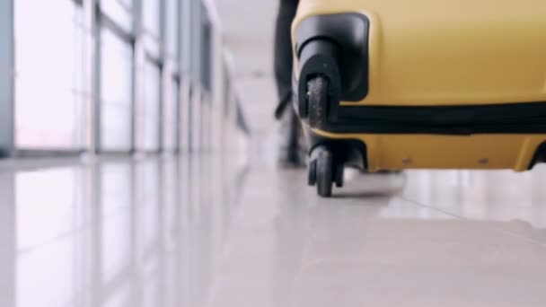 Un viajero con una maleta está pasando por una sala del aeropuerto — Vídeo de stock
