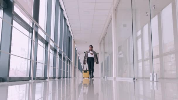 Een reiziger met een koffer gaat door een luchthavenhal. — Stockvideo