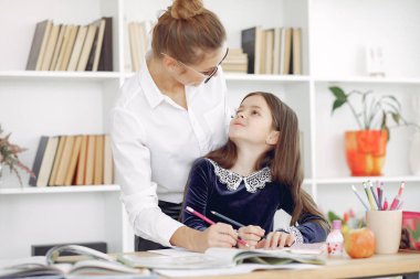 Küçük kızla evde ders çalışan bir öğretmen.