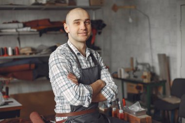 Stüdyodaki adam deri eşya üretiyor.