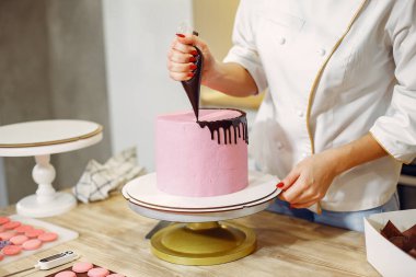 Üniformalı pastacı pastayı süslüyor.