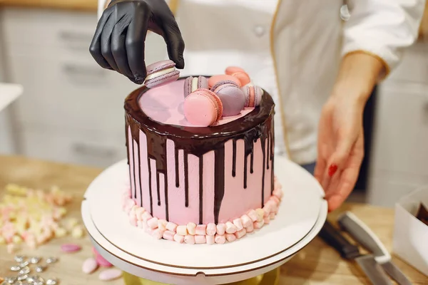 Cukrář v uniformě zdobí dort — Stock fotografie