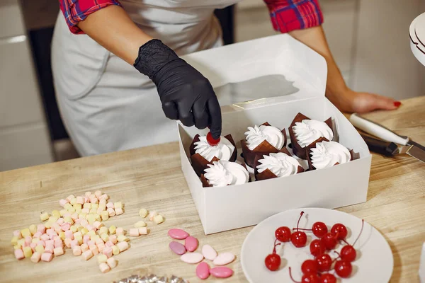 Confectioner in a uniform decorates the cakes