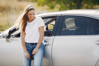 Arabanın yanında duran zarif kadın.