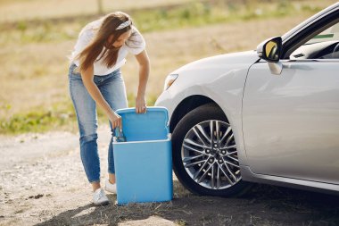 Arabanın yanında duran zarif kadın.