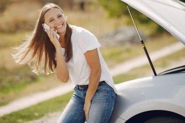 Arabanın yanında duran zarif kadın.