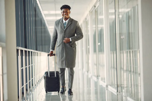 Eleganter schwarzer Mann mit Koffer am Flughafen — Stockfoto