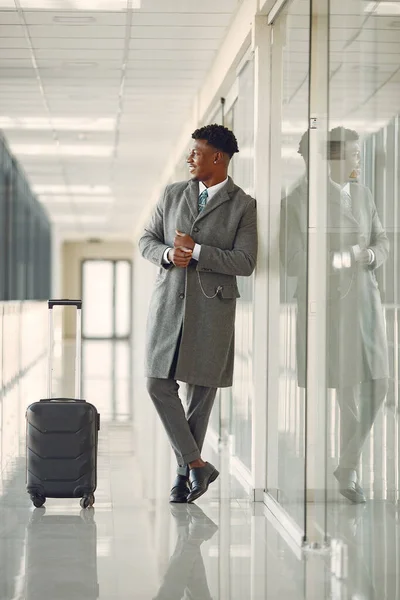 Eleganter schwarzer Mann mit Koffer am Flughafen — Stockfoto