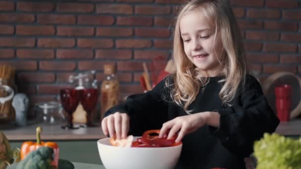 Klein jong meisje maakt een salade van verse groenten — Stockvideo