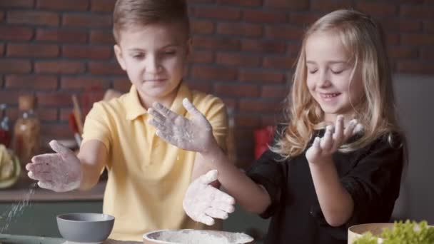 Chico y chica están cocinando y aplaudiendo en harina — Vídeo de stock