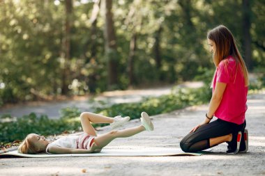Anne ve kızı yaz parkında yoga yapıyor.
