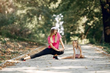 Anne ve kızı yaz parkında spor yapıyor.