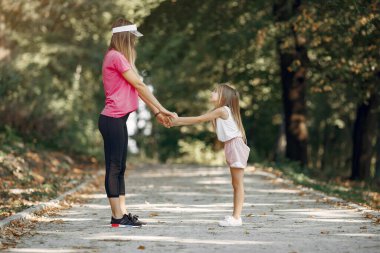 Anne ve kızı yaz parkında spor yapıyor.