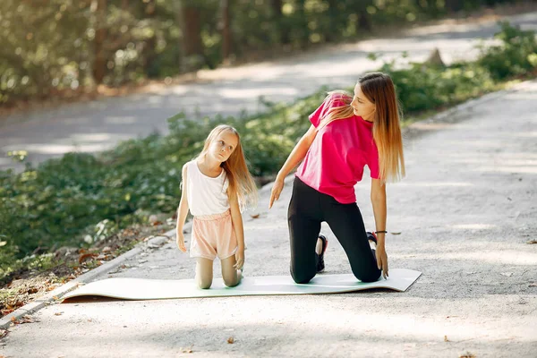 Matka z córką uprawia jogę w letnim parku — Zdjęcie stockowe
