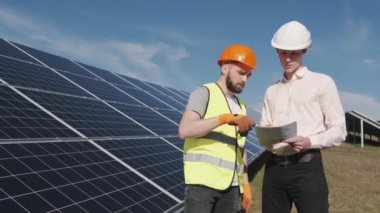 İşadamı ve işçi güneş enerjisi istasyonunda projeyi tartışıyorlar.