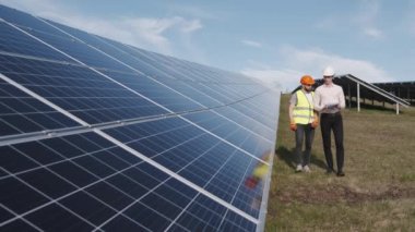 Bir işadamı ve bir işçi güneş enerjisi istasyonunda yürüyorlar.
