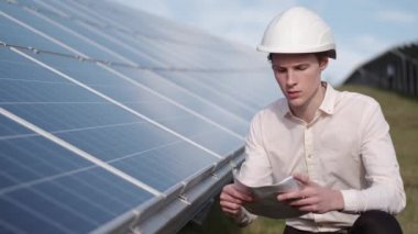 Bir adam fabrikadaki güneş enerjisi panelini kontrol ediyor.