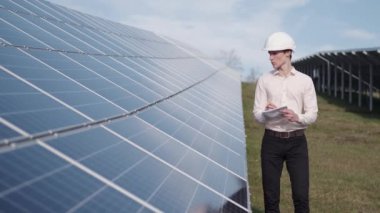 Bir adam fabrikadaki güneş enerjisi panelini kontrol ediyor.