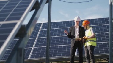 İşadamı ve işçi güneş enerjisi istasyonunda projeyi tartışıyorlar.