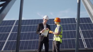 İşadamı ve işçi güneş enerjisi istasyonunda projeyi tartışıyorlar.