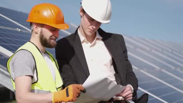 El empresario y el trabajador están discutiendo documentos de pie cerca de las baterías solares fuera — Vídeo de stock