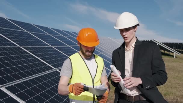 Επιχειρηματίας και εργαζόμενος είναι στο σταθμό ηλιακής ενέργειας συζητώντας το έργο — Αρχείο Βίντεο
