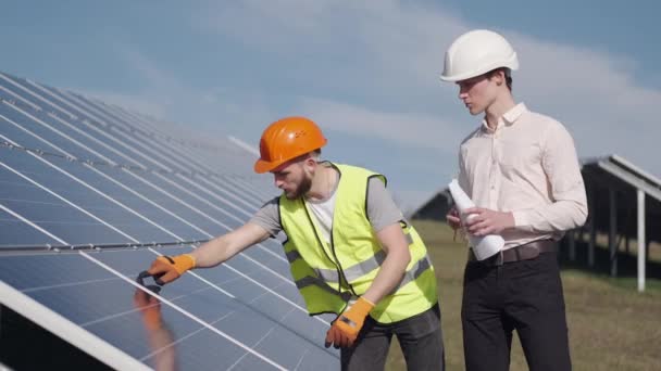 Бизнесмен и рабочий вместе проверяют солнечные батареи снаружи — стоковое видео