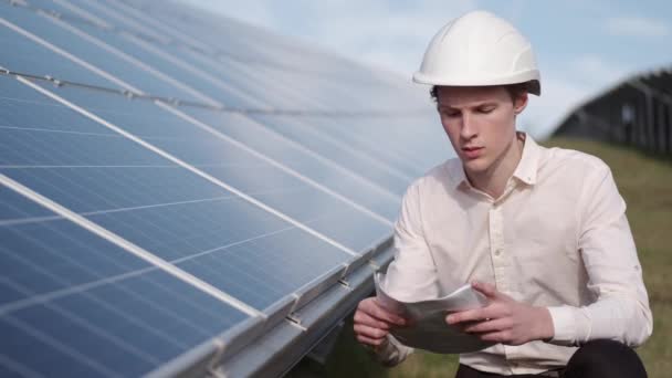 Um homem está a verificar o painel de energia solar na central. — Vídeo de Stock