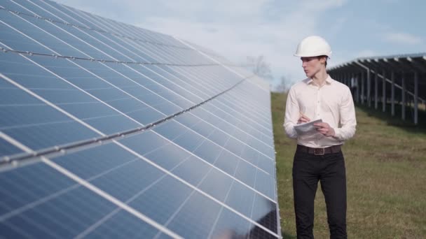 Um homem está a verificar o painel de energia solar na central. — Vídeo de Stock