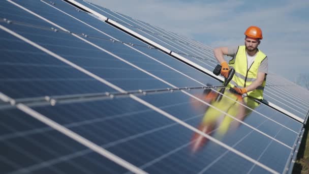 Engenheiro masculino em um uniforme está verificando a bateria solar fora — Vídeo de Stock